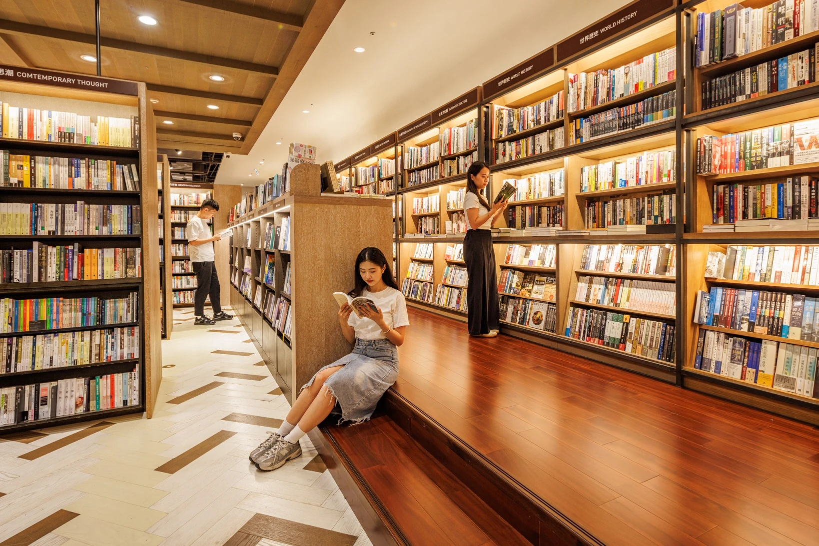 讀者在誠品松菸24小時書店的書架間專注閱讀