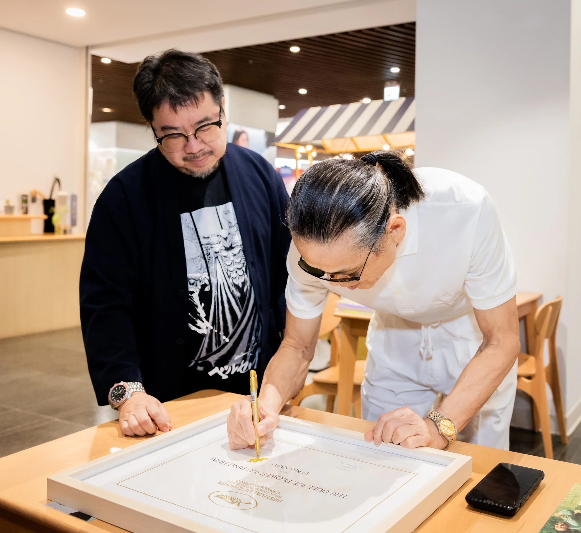 導演楊立國(右)為《魯冰花》入選坎城影展「經典單元」的入圍紀念證書親筆簽名,影視聽中心董事長褚明仁(左)在一旁觀看。