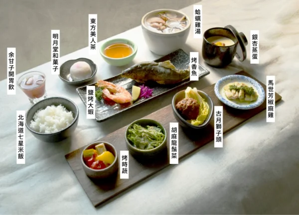 桌面上一字排開多道精緻的懷石料理餐點，包含烤香魚、鹽烤大蝦、椒麻雞、獅子頭、蒸蛋、和菓子與飲品等，旁邊皆附有白色字卡標示菜名。