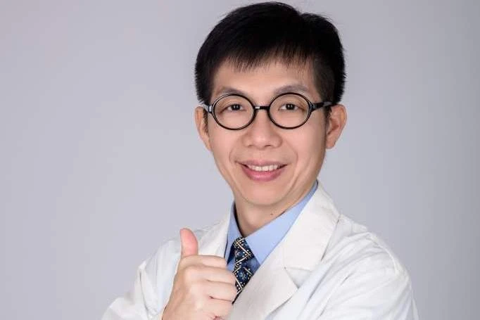 足踝專科醫師朱家宏穿著白袍、戴黑框眼鏡對鏡頭比讚微笑