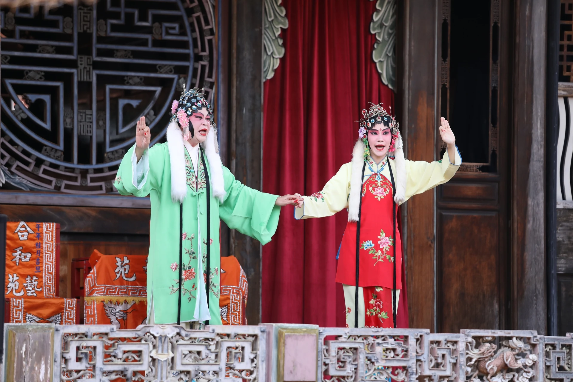 兩名身穿傳統戲曲服飾的演員在舞台上表演南管戲曲,一人著綠衣、一人著紅衣,姿態生動。