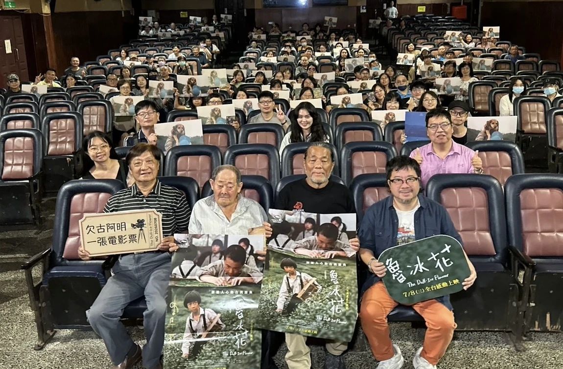 電影院內坐滿觀眾,前排嘉賓手持宣傳牌與海報向鏡頭展示。