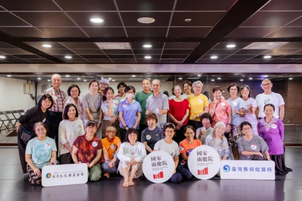 多位熟齡學員與工作人員在排練室內合影，部分學員手中拿著寫有「國家兩廳院」、「日月光文教基金會」、「臺灣集保結算所」字樣的標示牌。