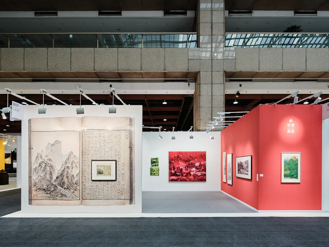 藝博會展場內的藝術品展示區,左側牆面展示巨幅古籍書畫複製件,右側為紅色牆面的畫廊攤位。