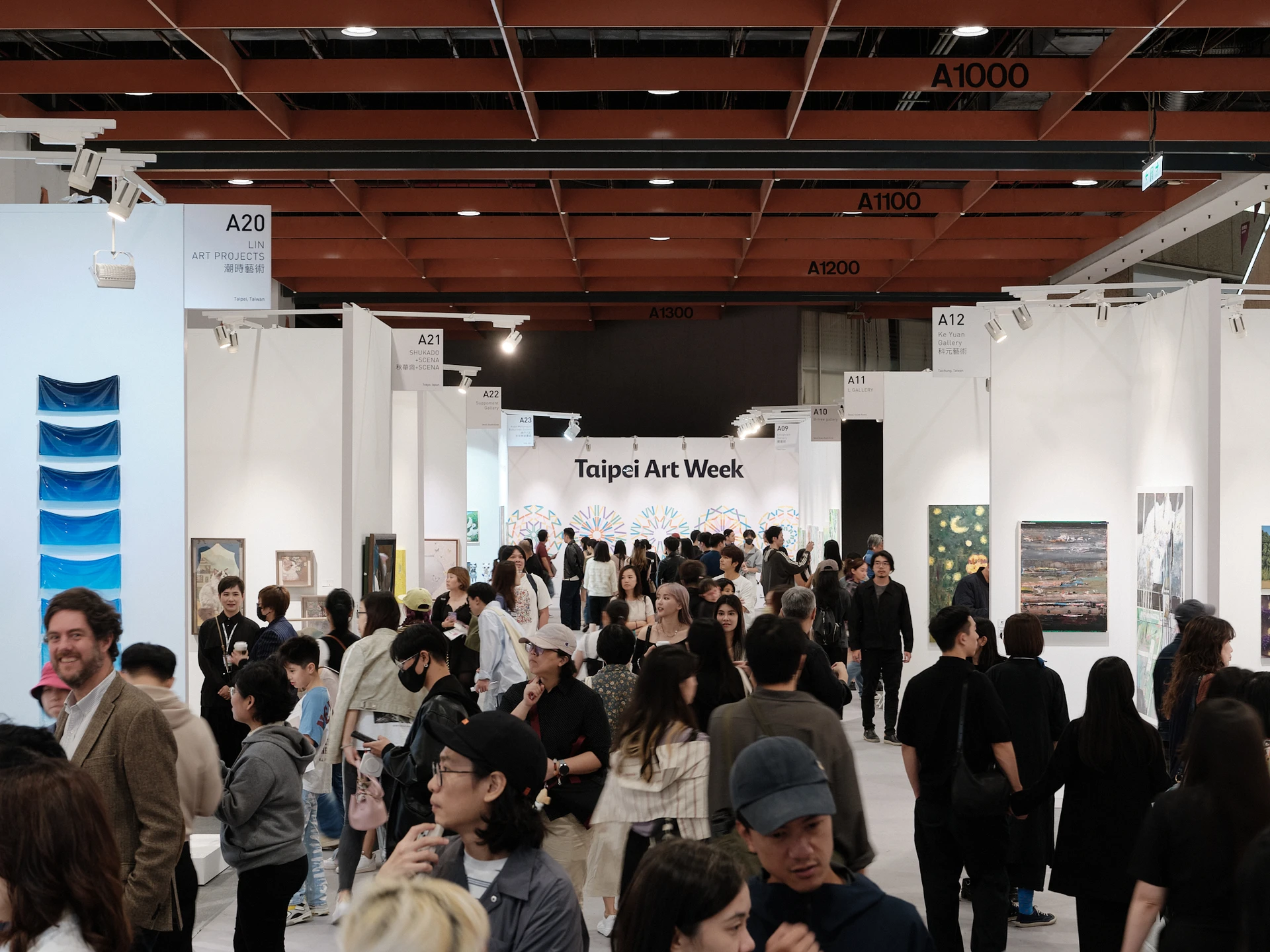 ART TAIPEI 展場走道上聚集大量觀展人潮,遠方可見 Taipei Art Week 字樣的白色背板。