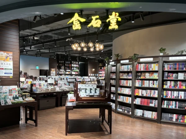 金石堂大江店內實景，上方有黃色金石堂招牌燈，下方為木質書架與書籍展示台。