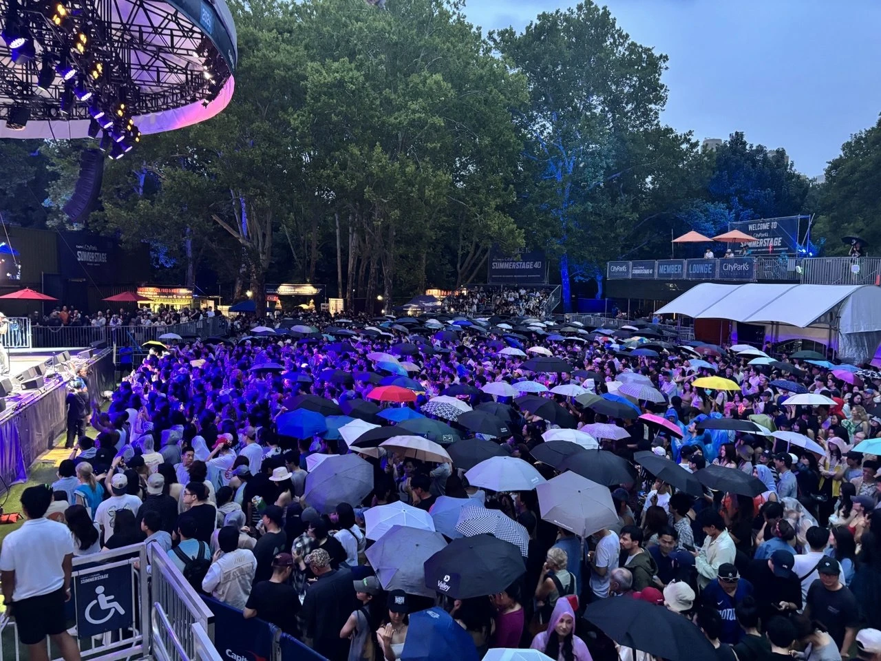 紐約中央公園SummerStage戶外音樂節現場,台下數千名觀眾撐著各式雨傘觀賞演出。