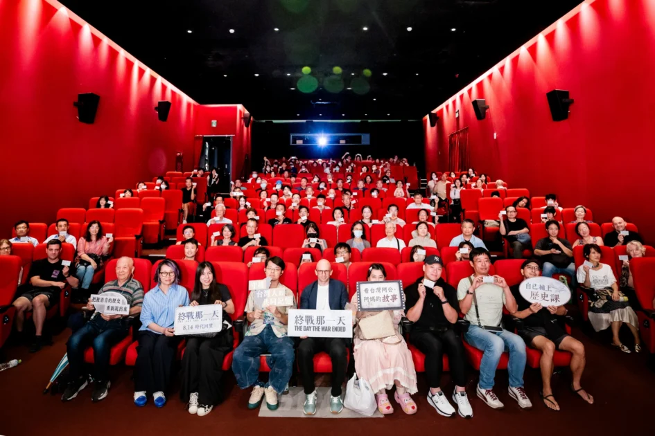 紀錄片《終戰那一天》首映會現場，導演、與談人與全場觀眾在紅幕影廳內舉著紀念票卡合影。
