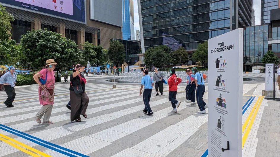 戶外廣場上多位民眾頭戴耳機，正在進行肢體伸展與跳躍的舞蹈互動。