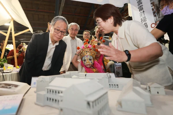 文化部長李遠與文資局長陳濟民等人在攤位前觀察臺中州廳建築模型，一旁有女性局長為其解說。