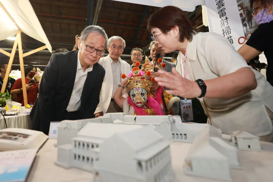 文化部長李遠與文資局長陳濟民等人在攤位前觀察臺中州廳建築模型，一旁有女性局長為其解說。