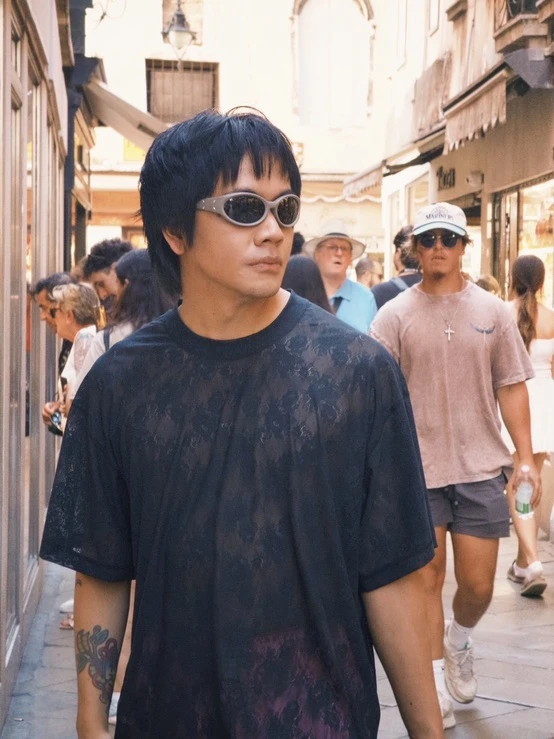 喬瑟夫戴著墨鏡走在歐洲街道上,身穿黑色上衣,背景有行人。